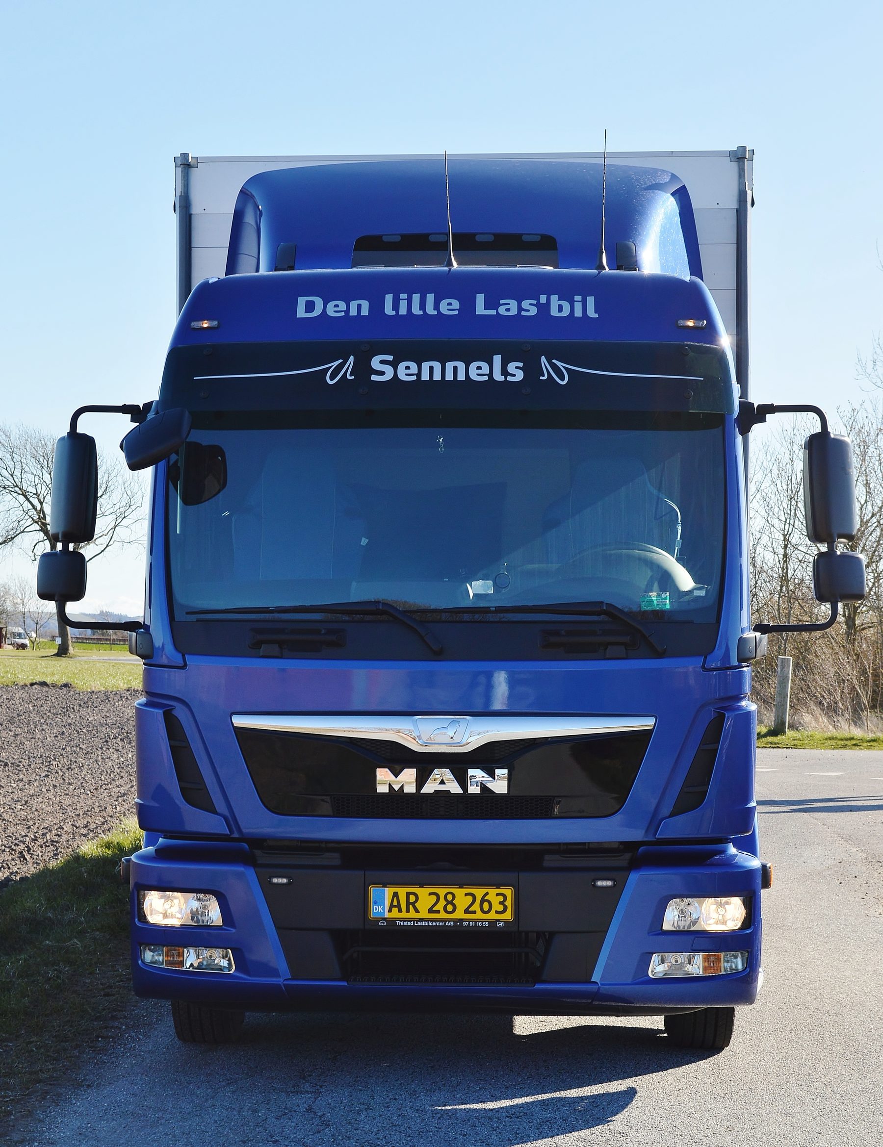 Lastbilen set forfra med firmanavnet Den Lille Las’bil i forruden